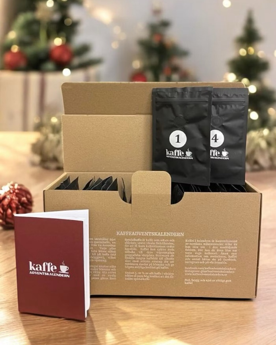 An open kraft box of the Swedish Kaffeadventskalendern with numbered black coffee pouches and a red booklet in front