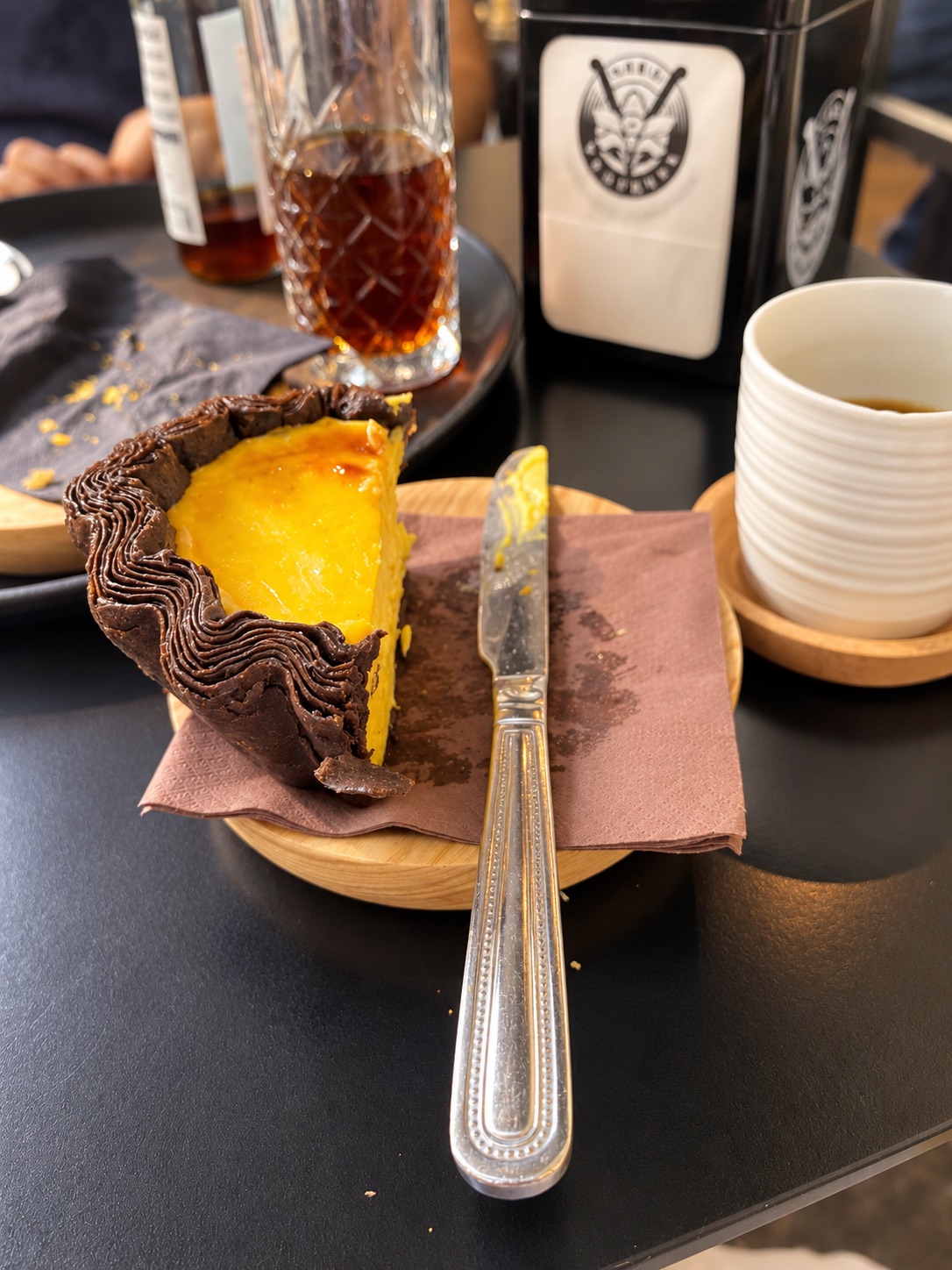 A slice of flan parisien with a cocoa croissant crust, next to a cup of filter coffee