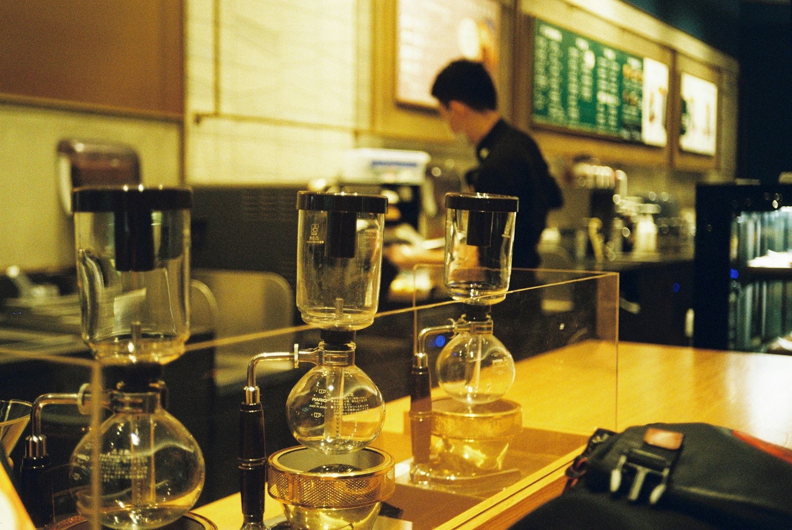 A row of siphon coffee makers on a café counter
