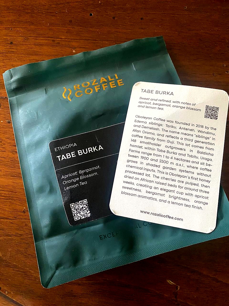 Front of the green Rozali Coffee Tabe Burka bag with its label, and the lot card beside it